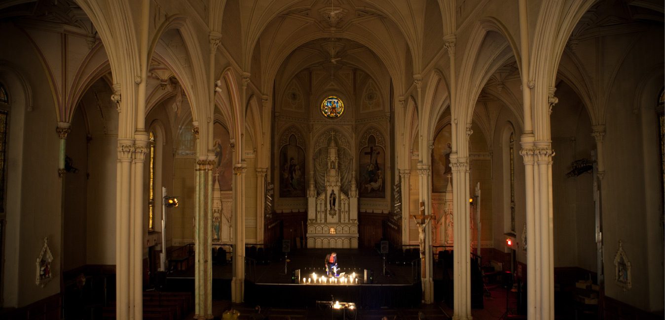 Performer on stage with experimental instrument in large catholic church.